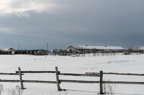 A fence and barn in the snow near a farm