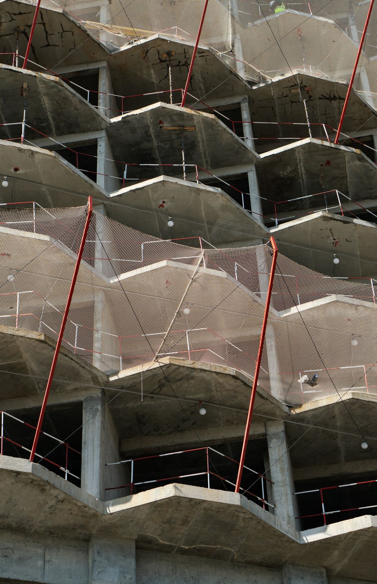 Fachada de edifício residencial em construção com estrutura de concreto e telas de proteção