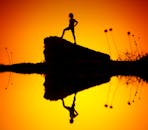 夕阳下，岩石上孩子的轮廓映在水中