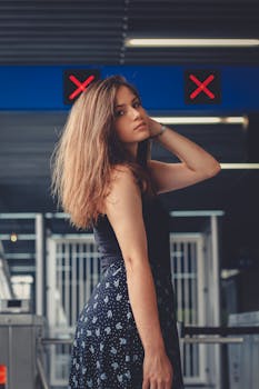 一位穿着时尚服装的优雅女子在现代化的公交车站摆姿势