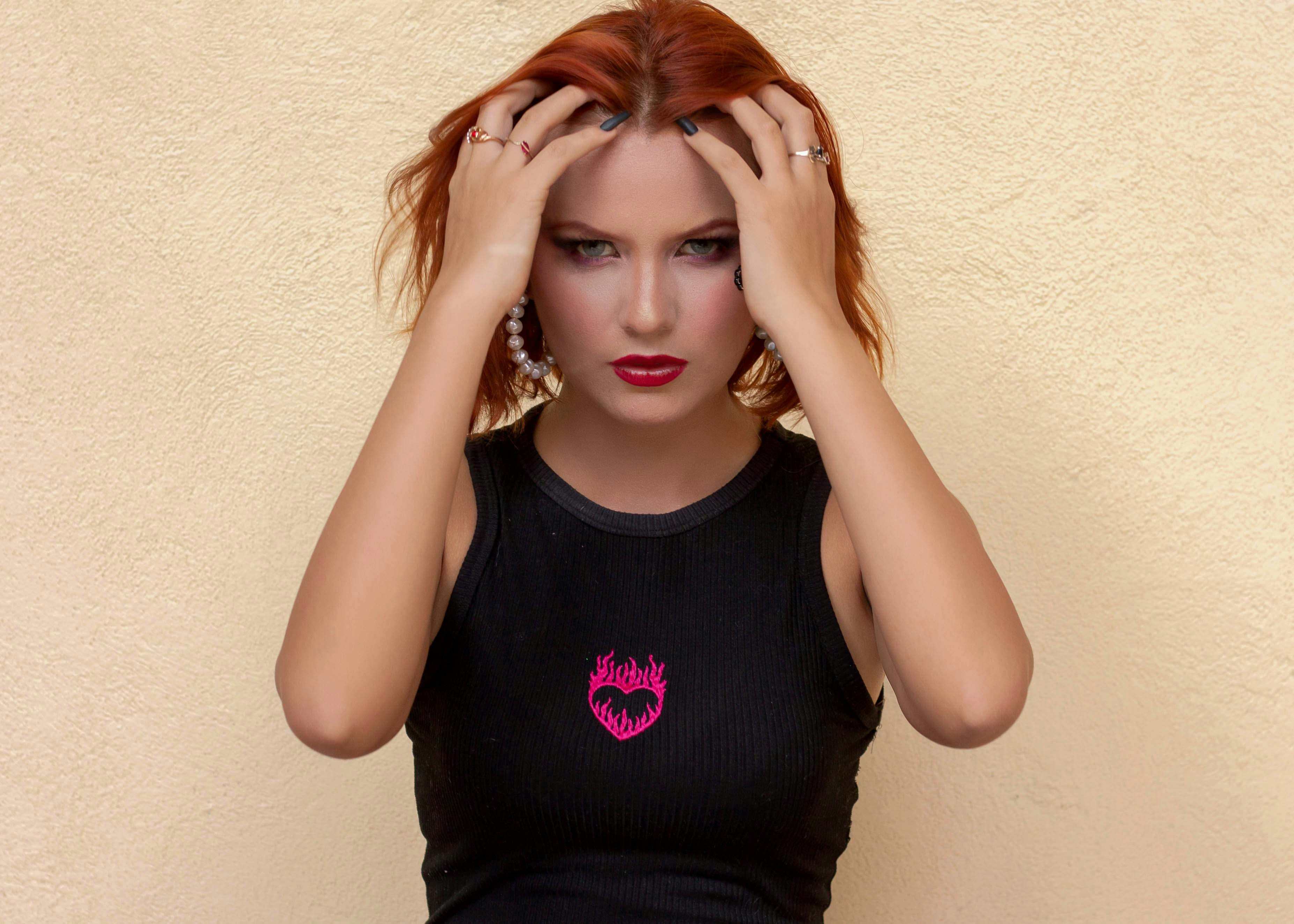 Striking portrait of a redhead woman in a black top, posing with confidence. Studio setting.