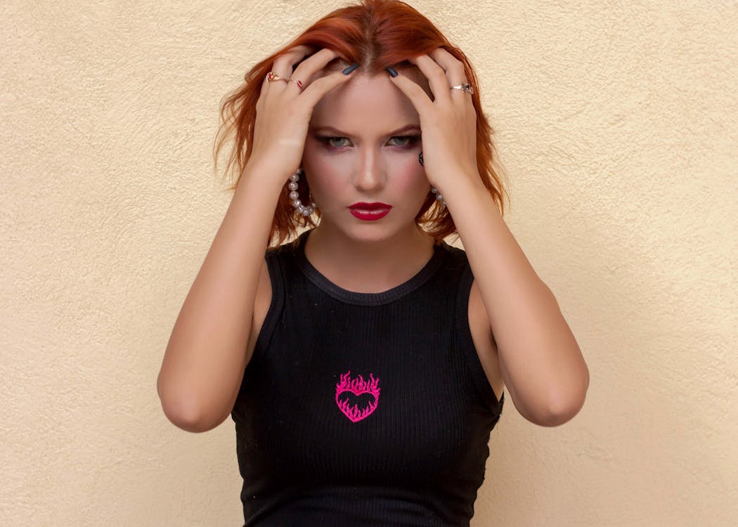 A woman with red hair is holding her head