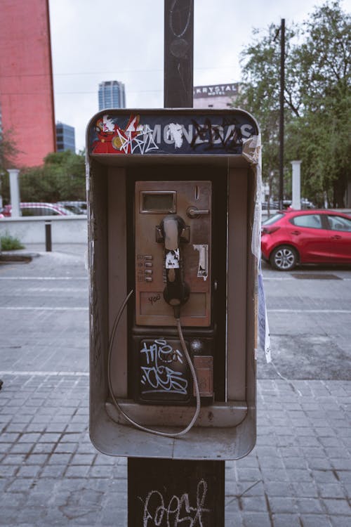 A pay phone with graffiti on it in a city