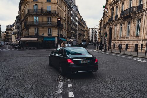 Free Elegant black Mercedes-Benz taxi driving through charming Paris streets, highlighting urban sophistication. Stock Photo