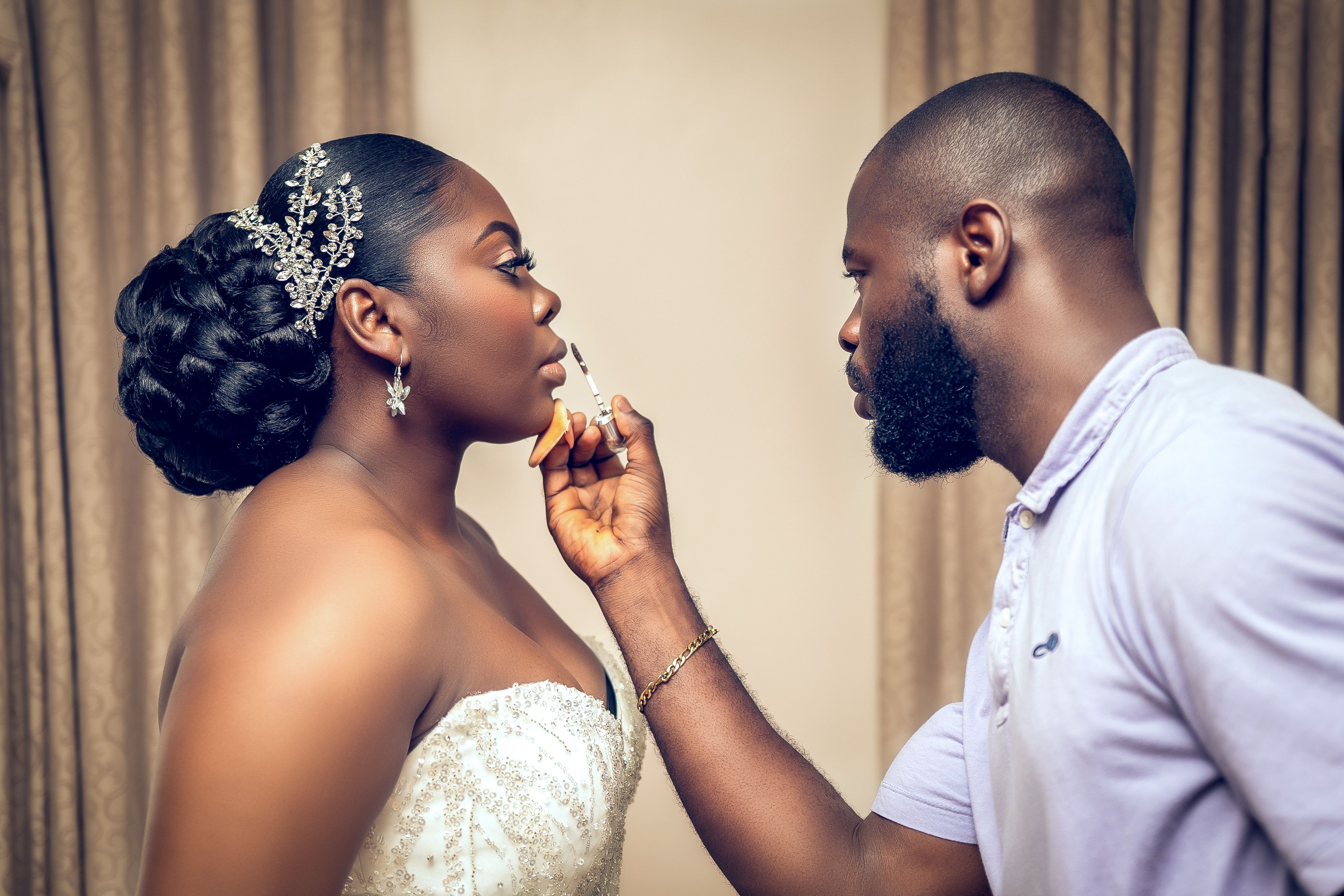 A makeup artist applies lipstick to a bride before her wedding ceremony, capturing a serene and elegant moment.