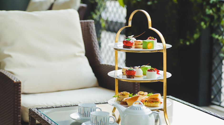 Luxurious afternoon tea arrangement with delectable treats and porcelain tea set in a cozy outdoor setting.