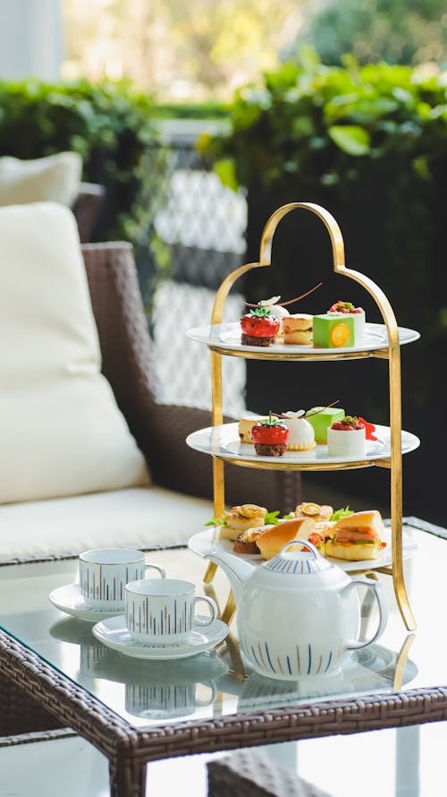 A three tiered tray with tea cups and pastries