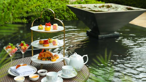 A table with tea and cakes on it next to a pond