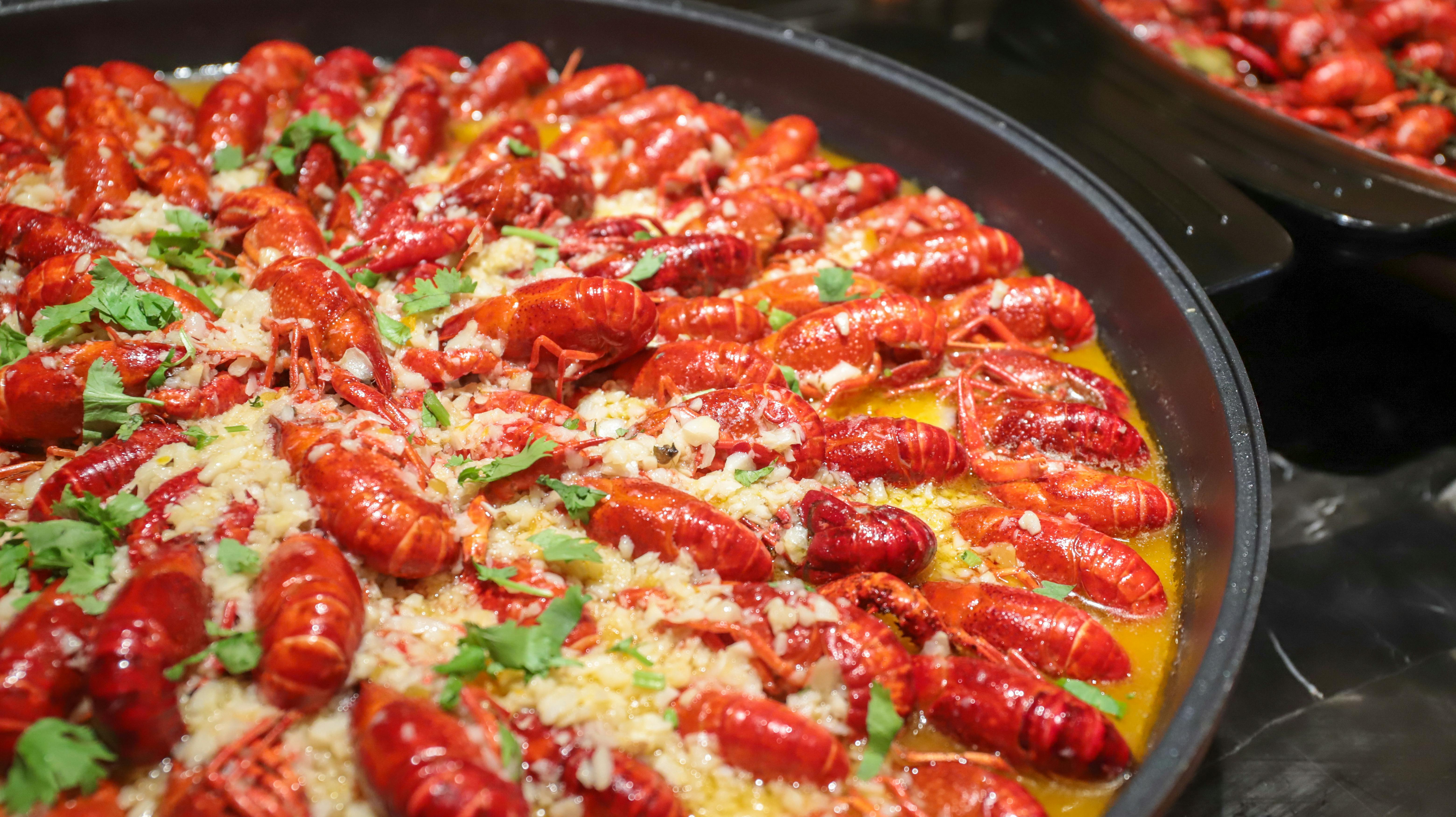 Red crawfish in a pan, sprinkled with herbs and garlic.