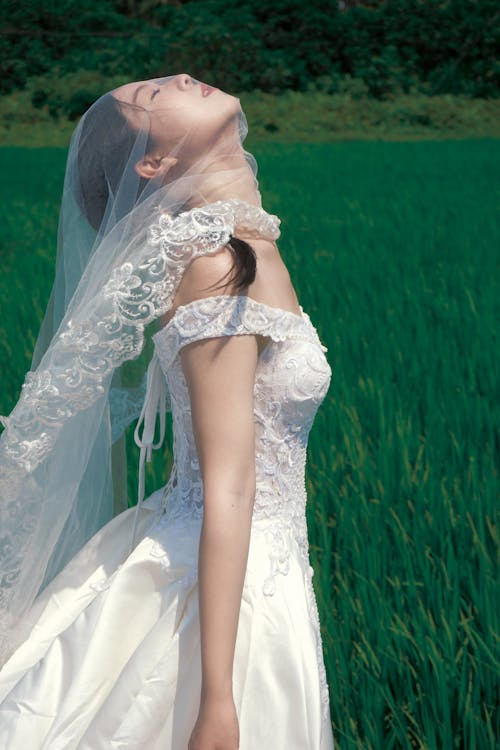 Brunette Woman in Wedding Dress Posing in Field