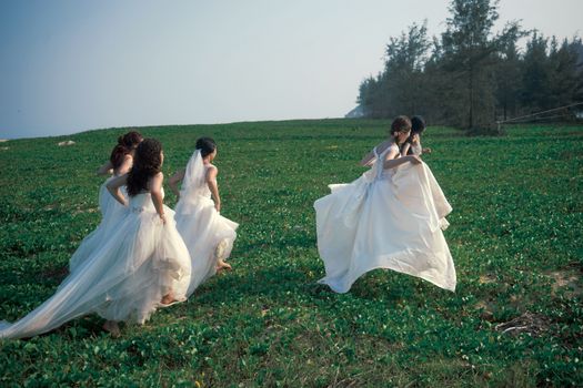 Brides in White Dresses Running in Field