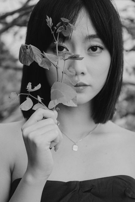 Black and white photo of a woman holding leaves, conveying a natural and artistic vibe.