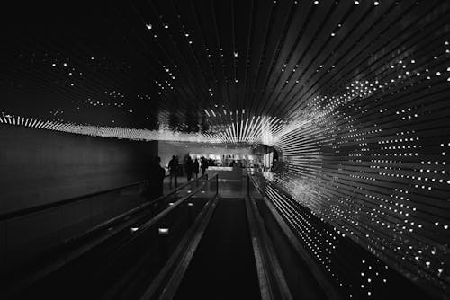 Greyscale Photo of People Walking Inside Tunnel