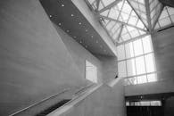 这张现代建筑的单色室内照片展现了极简主义设计，配有玻璃天窗和上升楼梯