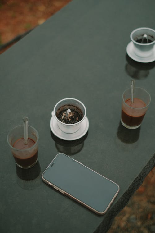 A table with two cups of coffee and a phone