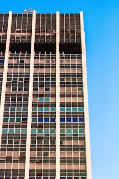 玻璃窗反射着明亮的蓝天，一座现代摩天大楼展现出城市建筑的风采