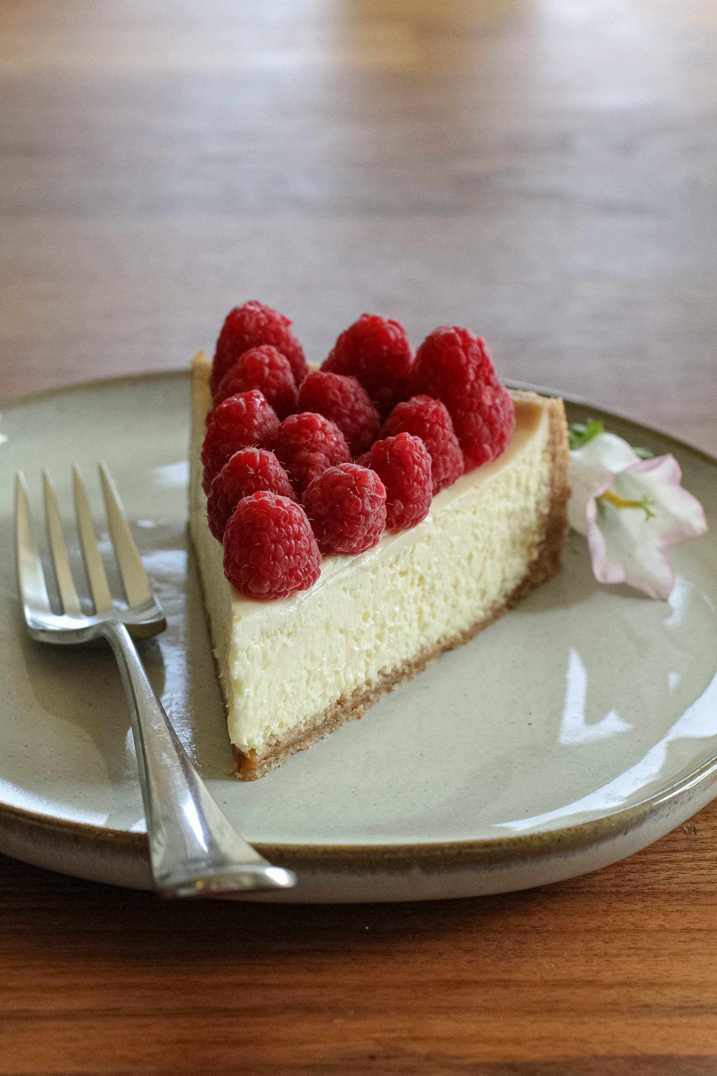 Slice of cheesecake with fresh raspberries on a plate, perfect for dessert lovers.