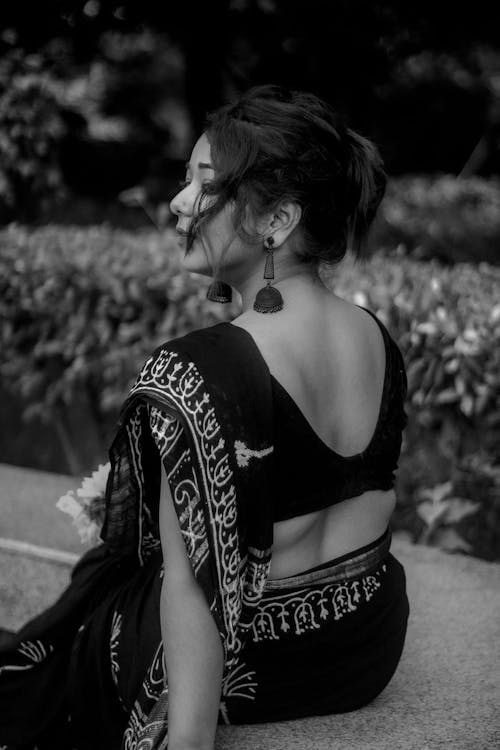 Black and white photo of woman in sari sitting on bench