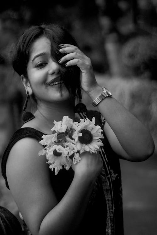 A woman is holding a bunch of sunflowers