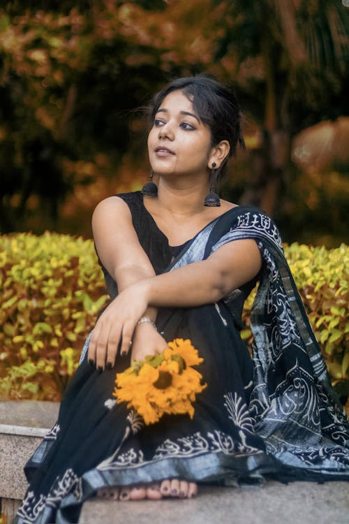 A woman in a black sari sitting on a bench