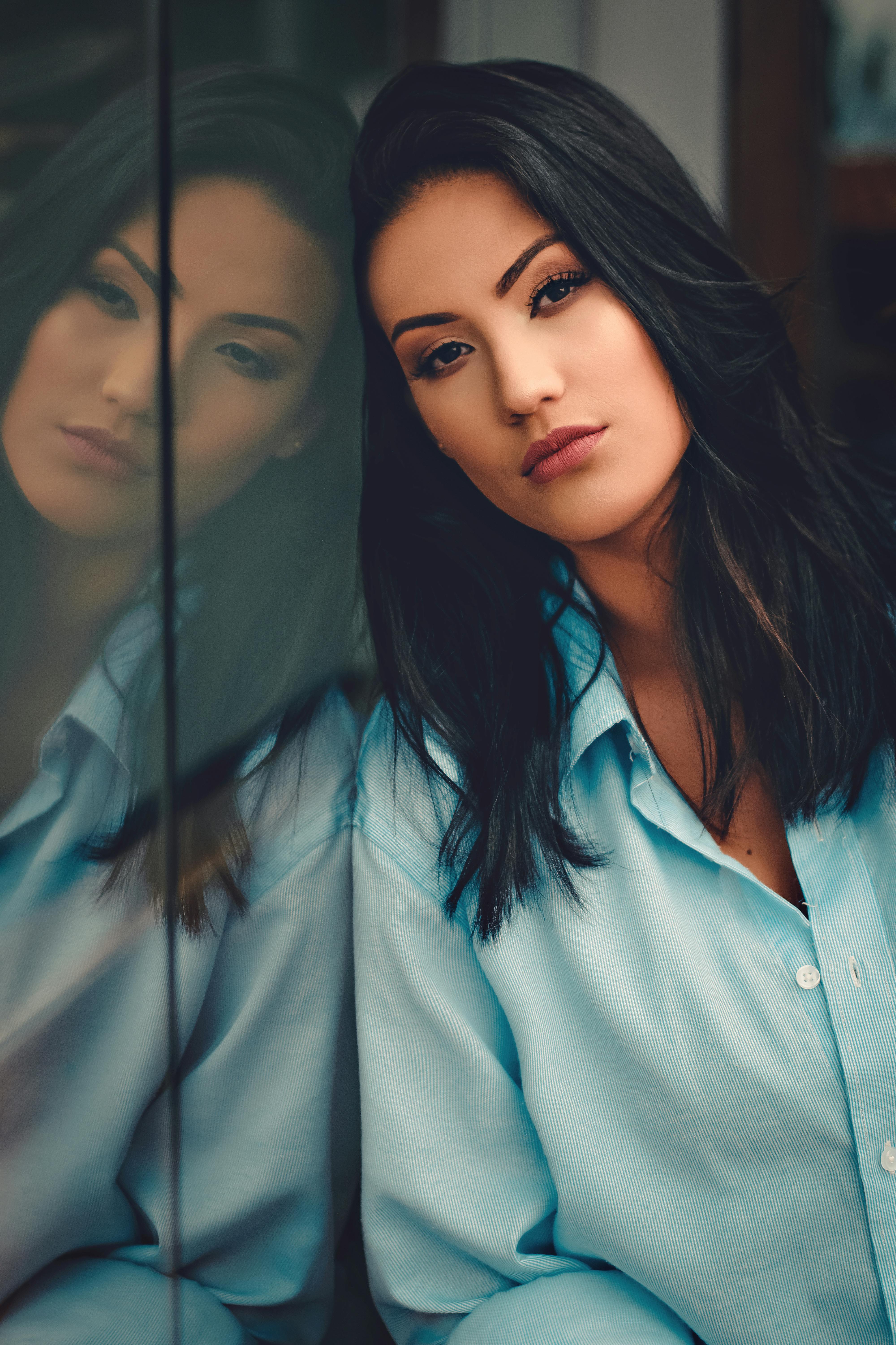 一位黑发女子的肖像靠在玻璃板上，姿势通过反射被捕捉