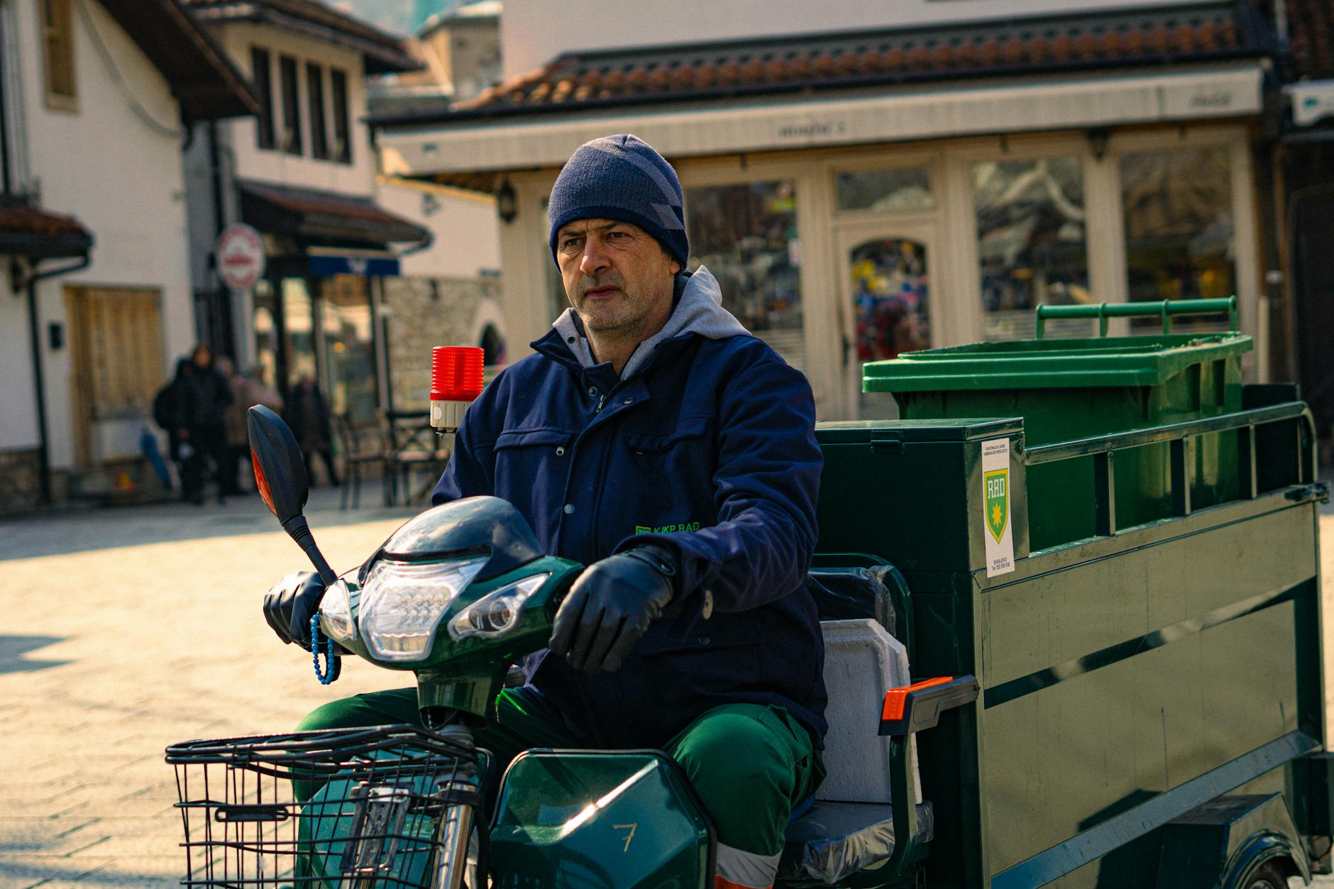 City worker riding a scooter in an urban area, showcasing local city life.