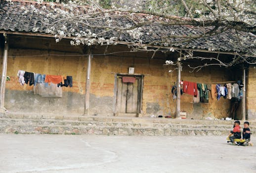 Children playing outside a rustic village house with laundry hanging, capturing rural lifestyle.