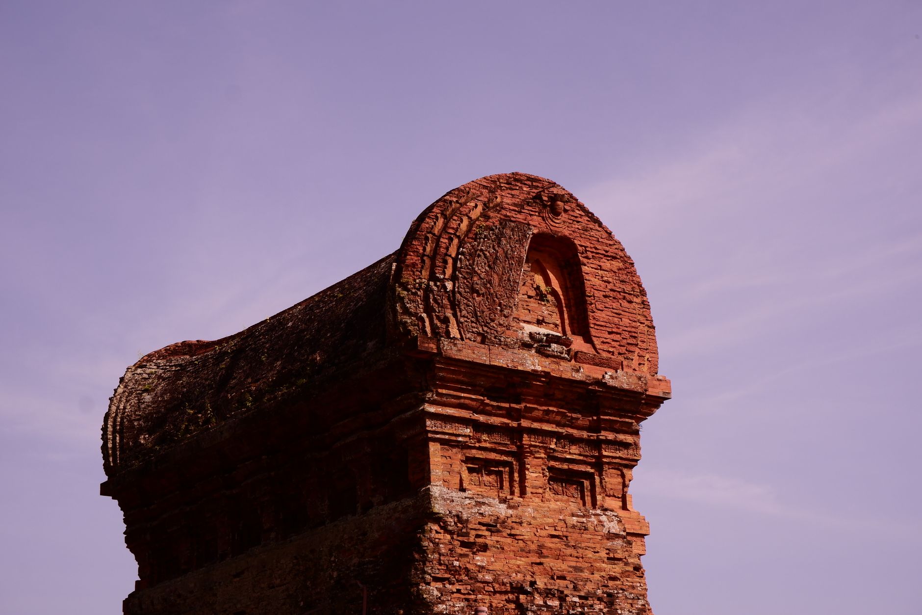 A close-up view of the historic Banh It Tower in Vietnam with a vibrant purple sky backdrop.
