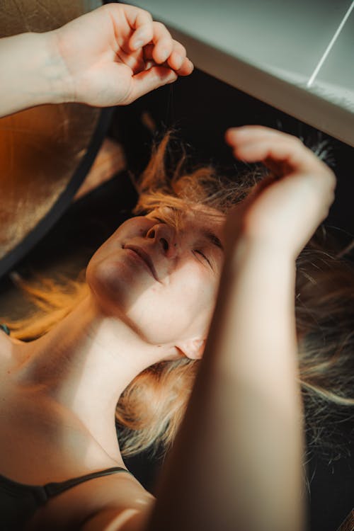 A woman laying on her back with her hair blowing in the wind