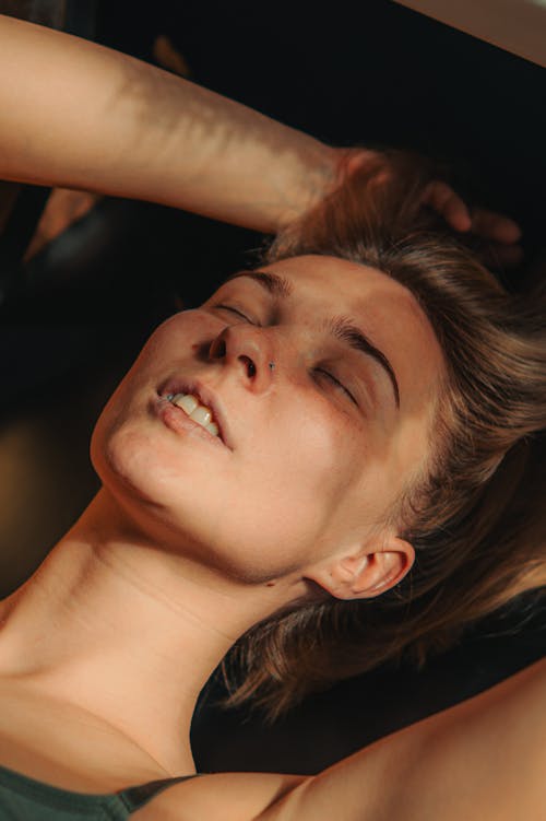 A woman laying on a bed with her head in the air