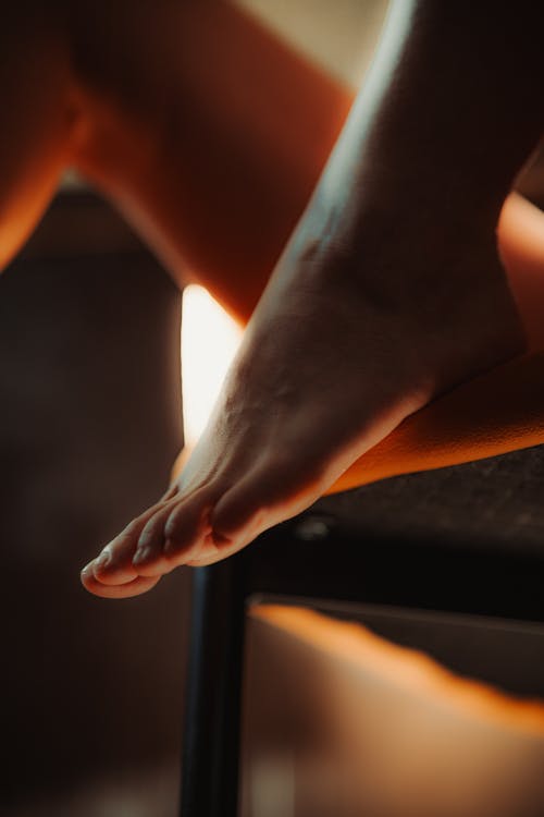 A woman's feet are on a chair with a candle
