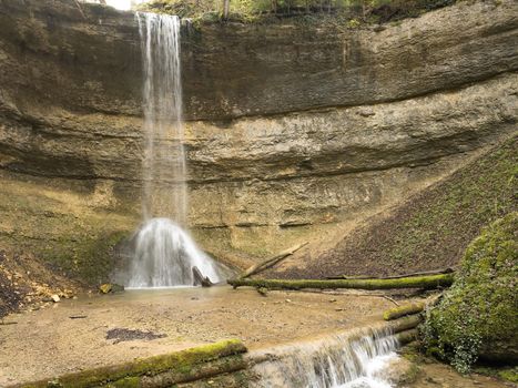 A peaceful waterfall flowing over a rocky cliff in a secluded, natural setting.