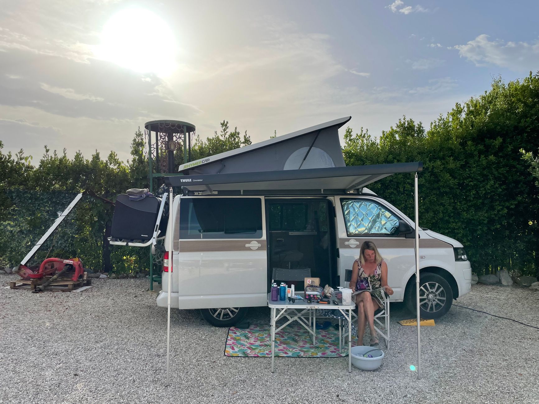Woman relaxing outside a camper van in Ripatransone, Italy, during a sunny day.
