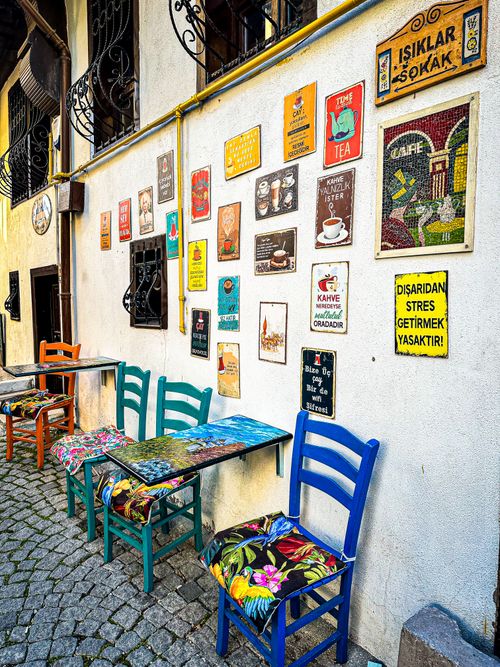 Free Outdoor cafe scene with vibrant chairs and eclectic wall decorations in a charming street setting. Stock Photo