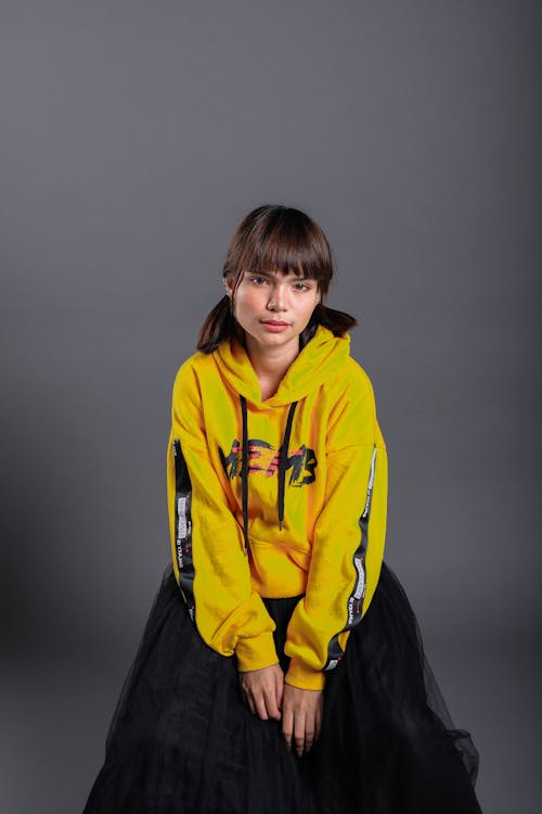 Sitting Woman Wearing Yellow Pullover Hoodie and Black Maxi Skirt