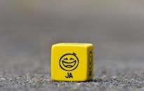 黄色骰子的特写，上面印有象征幸福和乐趣的笑脸表情符号