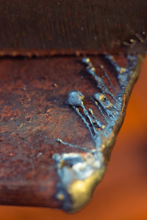 Melted silver over the corner of a rusted metal board