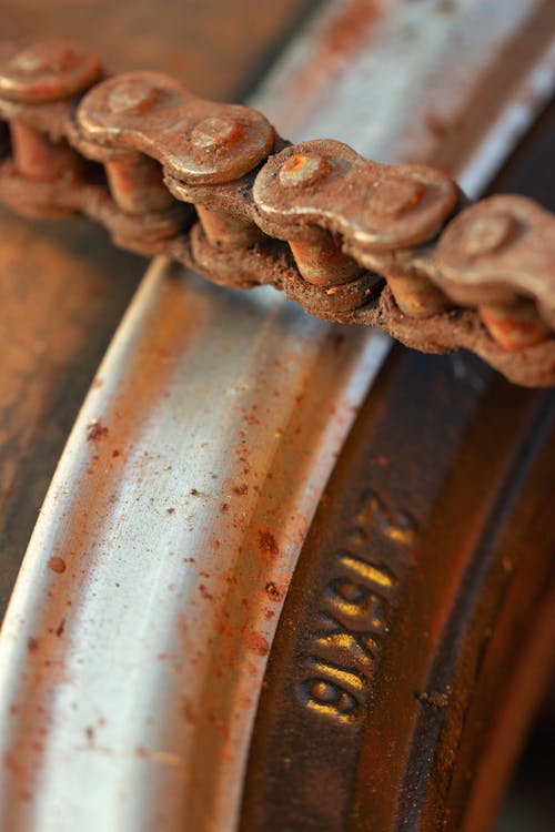 Rusted bicycle chain laying on metal inner rim of wheel