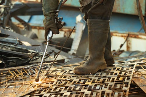 Man standing on a pile of metal sheets and soldering