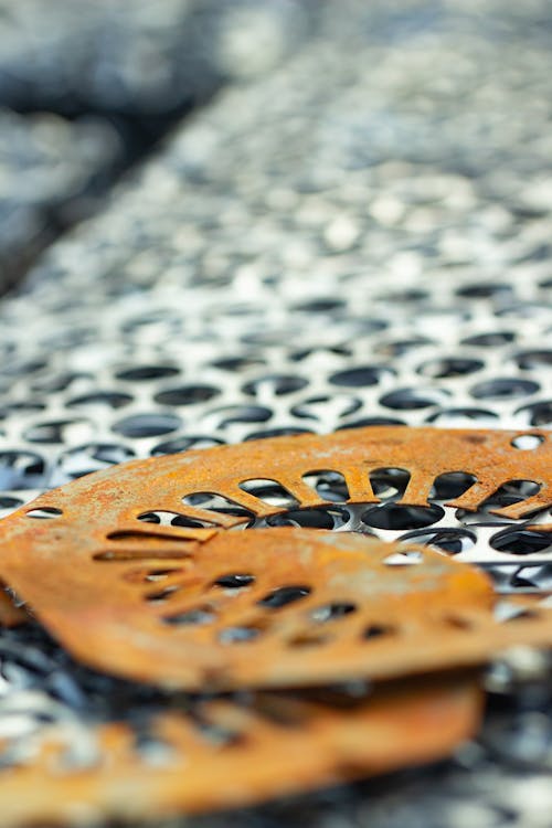 Orange metal pieces lying on top of a pile of metal sheets