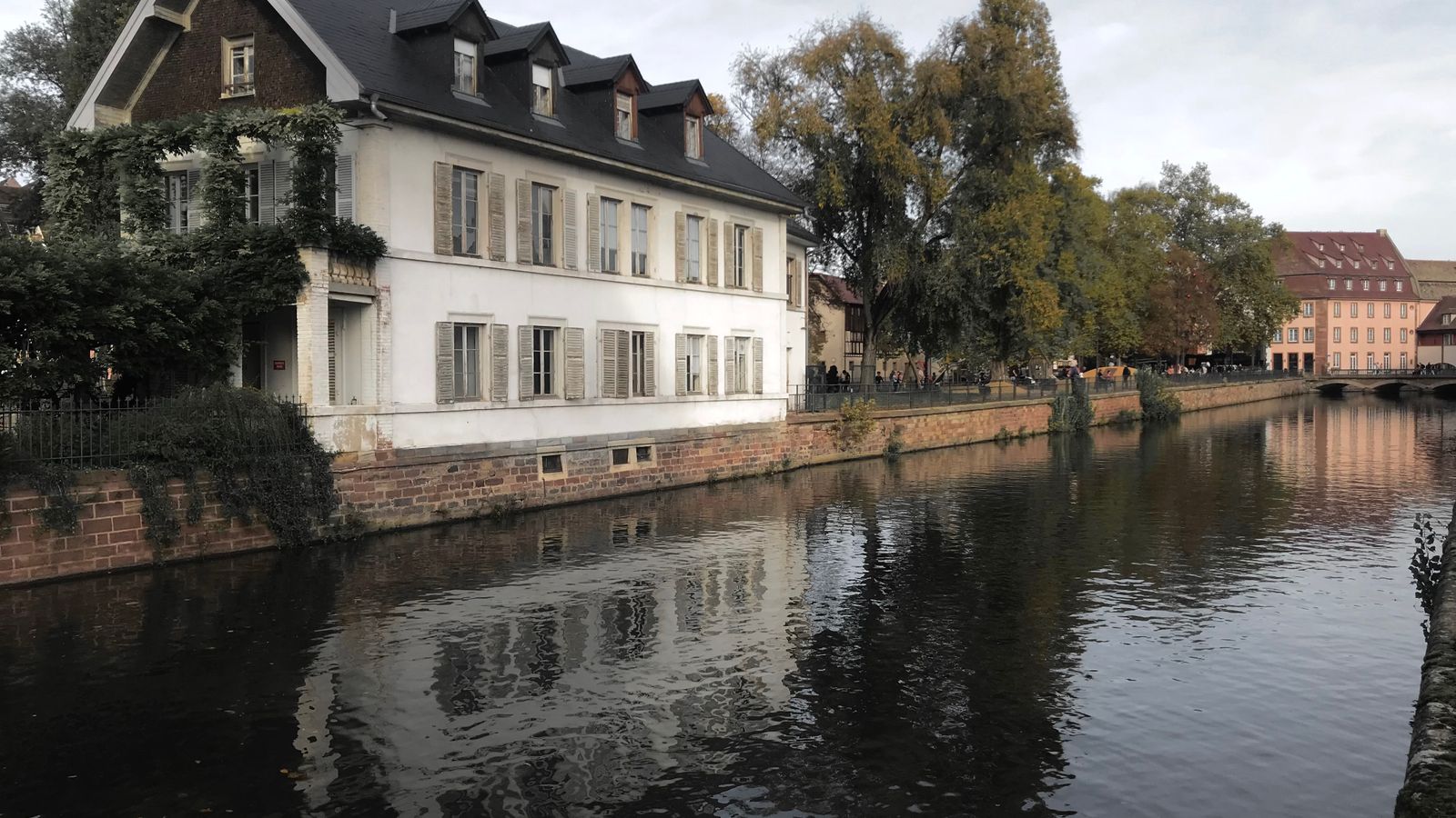 Maison ancienne se reflétant dans l'eau calme d'un canal, bordée de quais en pierre.