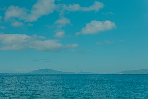 Free Serene seascape featuring a calm ocean under a bright blue sky with scattered clouds. Stock Photo