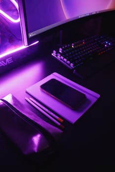 Sleek workspace with neon lights, keyboard, and notebook, creating a tech-focused atmosphere.