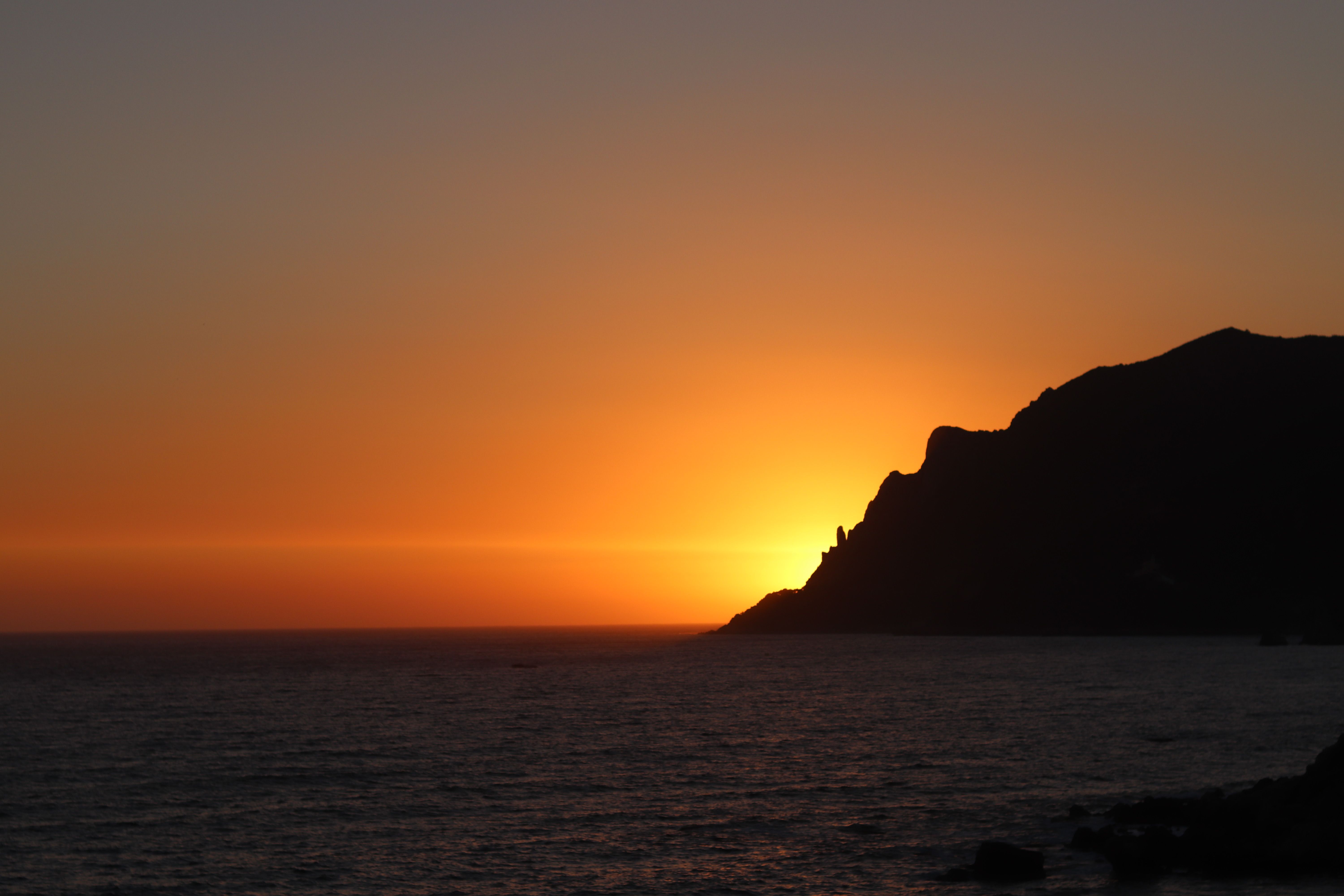Stunning sunset casting a warm glow over the sea and cliffs in Corfu, Greece. - Corfú