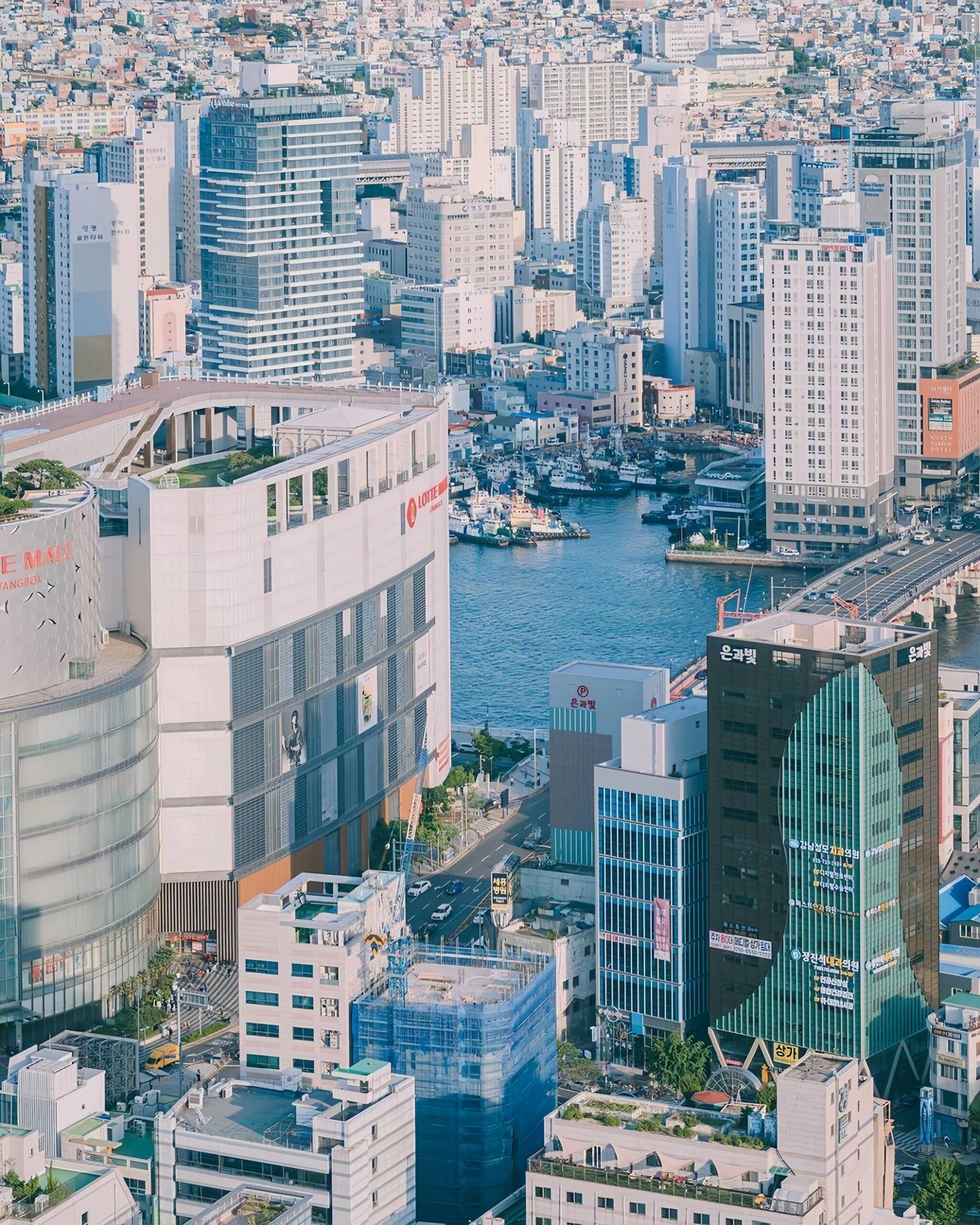 aerial view of downtown busan with boats in the harbor surrounded by skyscrapers