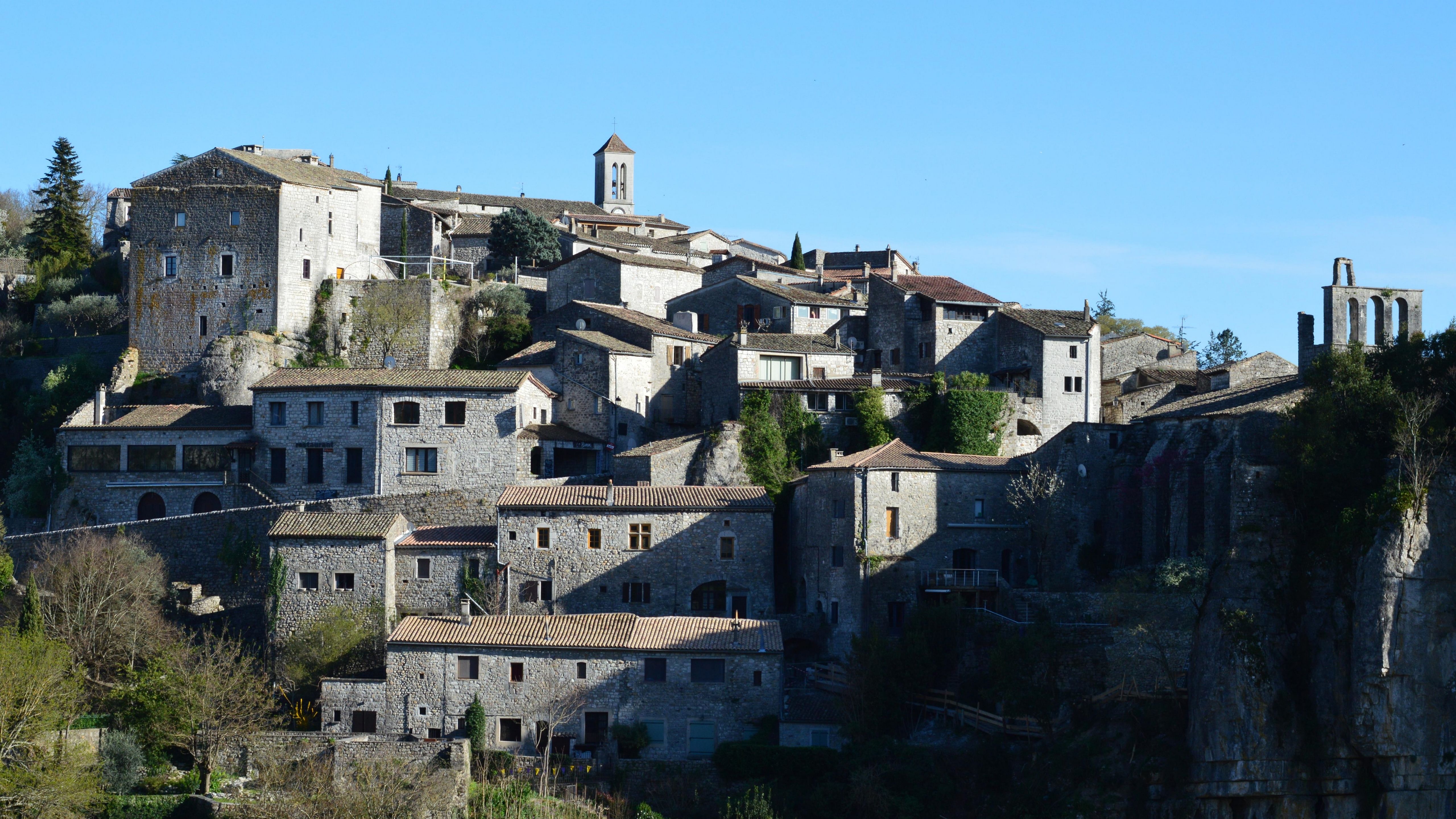 A scenic view of Balazuc village in France with stone buildings under a clear sky.