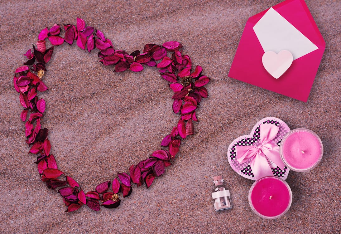 Pink Flower Petals and Pink Envelop on Top of Sand