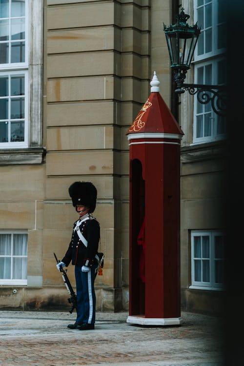 A guard stands outside a building with a red telephone