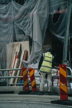 Construction worker in Malmö, Sweden, standing near building scaffolding.