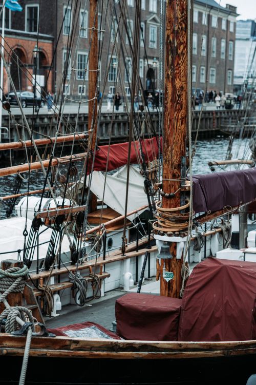 Free Vintage wooden ship moored in a canal amidst historic Copenhagen architecture. Stock Photo